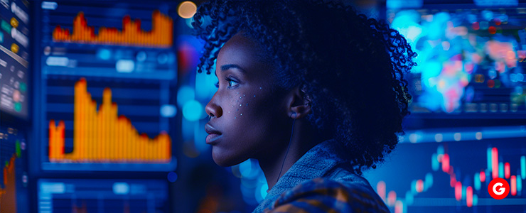 A woman analyzing stock market graphs on a screen.